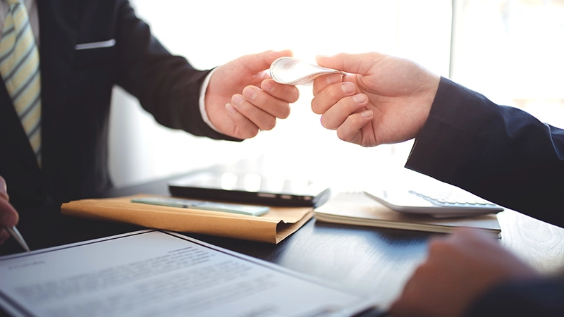 Business people negotiating contracts Collaborate on paperwork at the desk and sign a contract and handing a folded stack of cash to the other person.